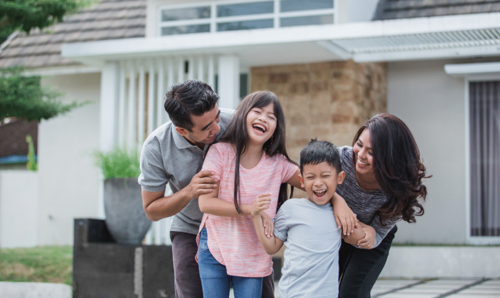 Happy family smiling outside their newly bought house.